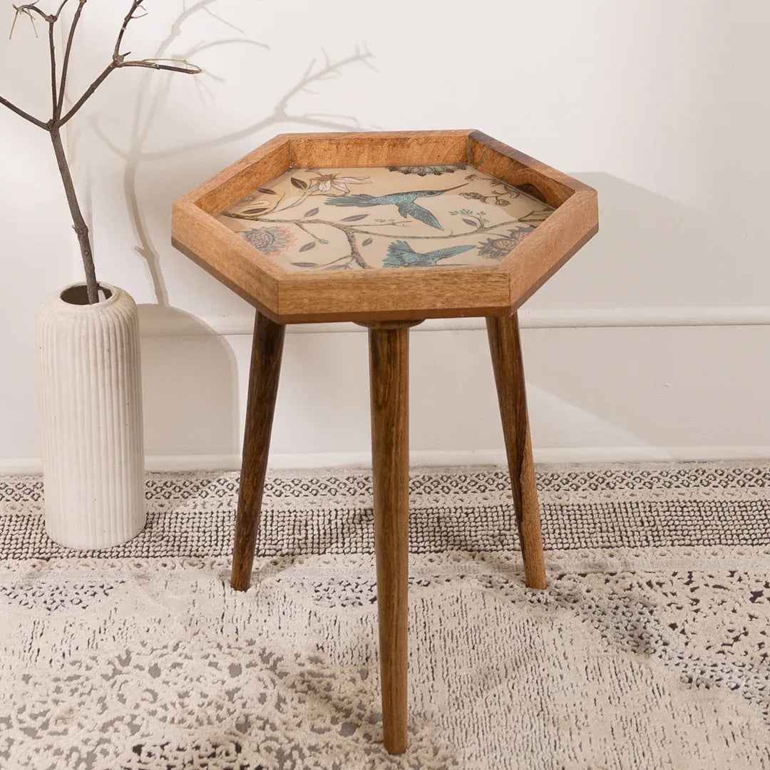 Hexagonal wooden side table with decorative inlay in a room setting.