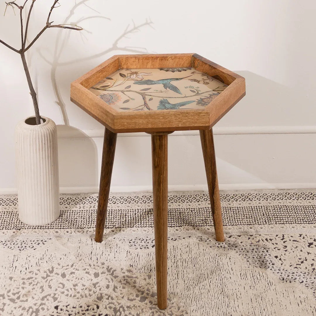 Hexagonal wooden side table with decorative inlay in a room setting.
