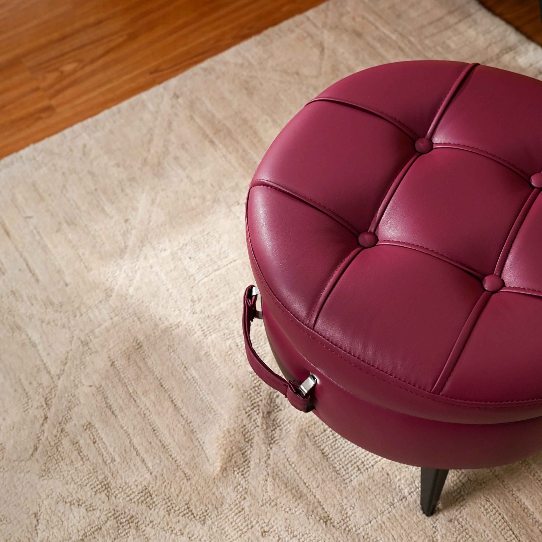 Round red cushioned stool on a beige carpet