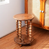 Wooden side table with spiral legs on a wooden floor next to a cabinet.
